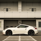 a white nissan fairlady z nismo parked in front of the garages at a race track in japan